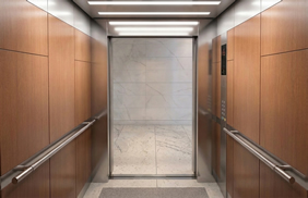 Conozca una cabina de ascensor con acabados en madera, pasamanos de acero e iluminación; solicite una solución cómoda y accesible de Ascensores Fahenn en Bogotá, Colombia